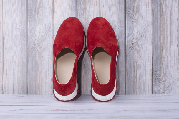 Красные женские кроссовки на фоне деревянных планок
 - Фото, изображение