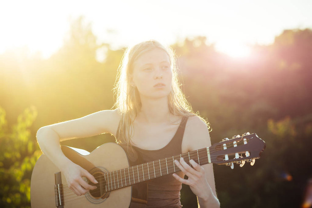 Woman playing acoustic guitar in summer park outdoor - Fotografie, Obrázek
