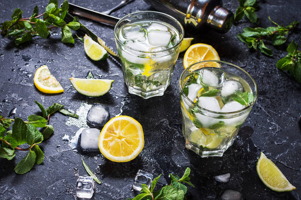 two glass of mojito cocktail with fresh lime and mint on a black stone board - Φωτογραφία, εικόνα