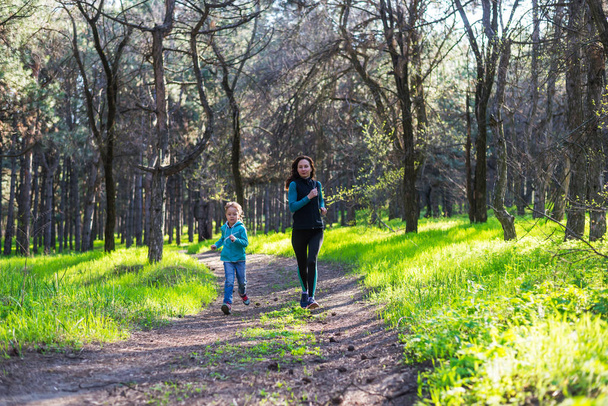 Morning jogging, mom and daughter are running along the forest trail, free space. - Fotografie, Obrázek