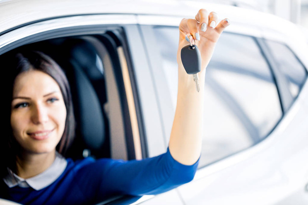 Sales woman showing the car key in auto showroom - Photo, image
