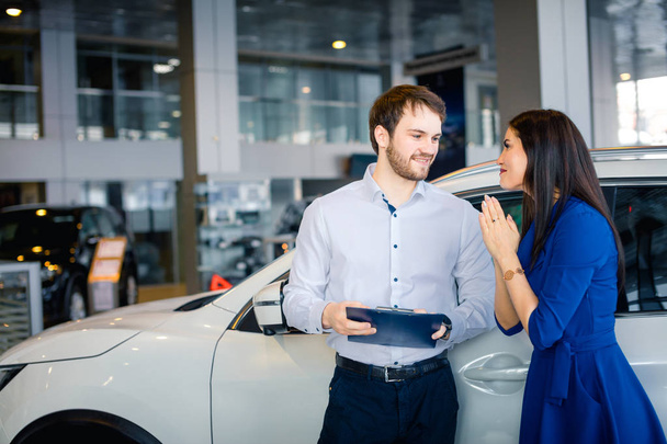 Grateful and happy young woman thanking her husband for present in dealership - 写真・画像