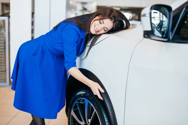 Visiting car dealership. Young woman hugging her new car - Zdjęcie, obraz