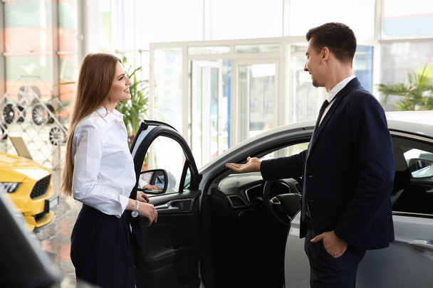 Young woman choosing new car with salesman in salon - Foto, Imagen