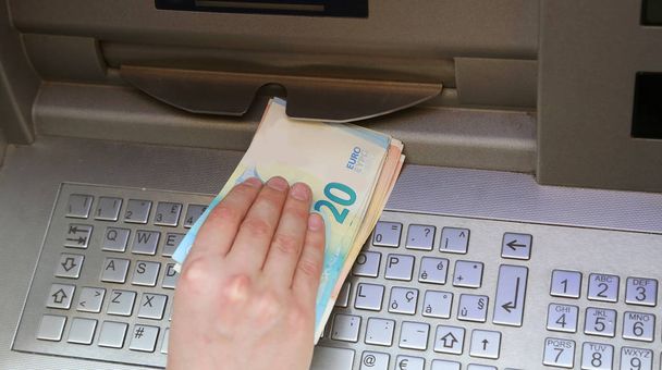 Мальчик берет деньги в банкомате в европейском городе
 - Фото, изображение