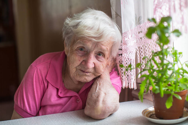 Retrato de mulher idosa sentada à mesa na casa
. - Foto, Imagem