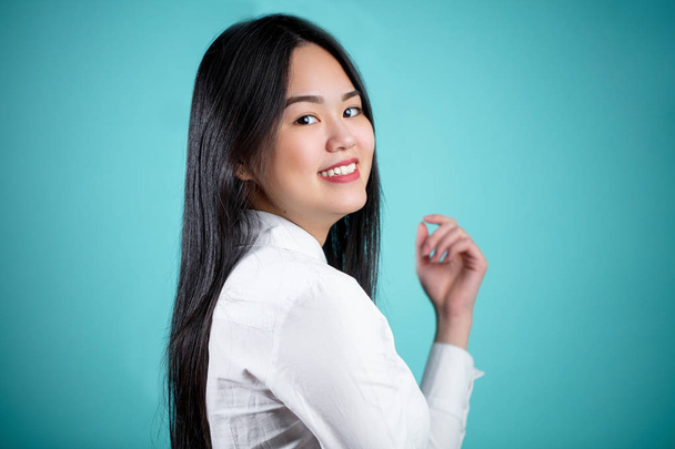 Gyönyörű fiatal ázsiai nő, elszigetelt kék háttér - Fotó, kép