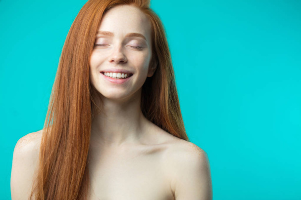 Modelo femenino con cabello rojo suelto y maquillaje natural posando encima
 - Foto, Imagen