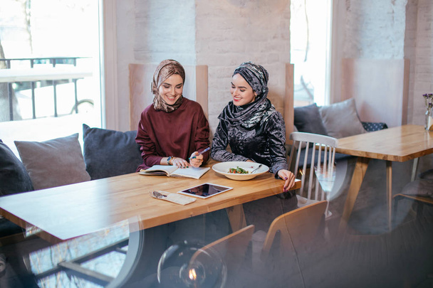 Two pretty muslim business woman in head scarf write in notebook - Photo, Image