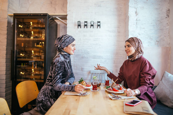Two Muslim women in cafe, friends meeting - Фото, изображение