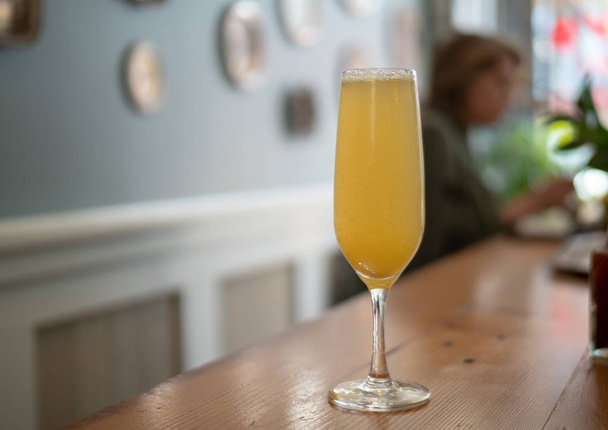 A wine glass filled with a mimosa at an indoor restaurant  - Photo, Image
