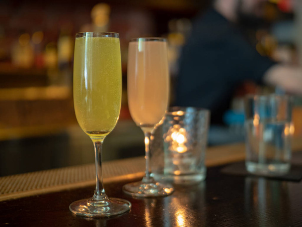 Twee wijnglazen gevuld met mimosa dranken met de barman in de rug - Foto, afbeelding