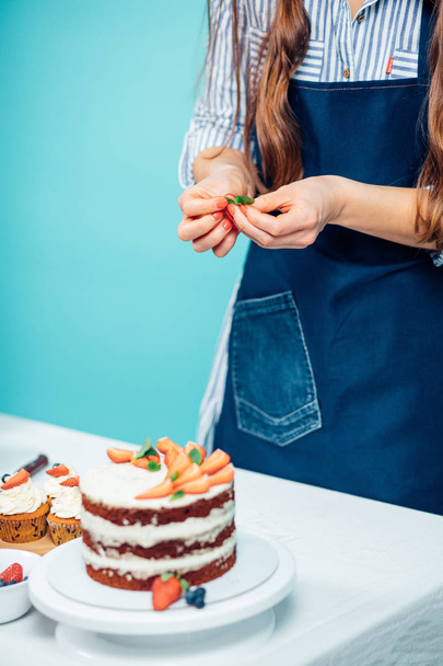 Woman decorating delicious cake - Foto, afbeelding