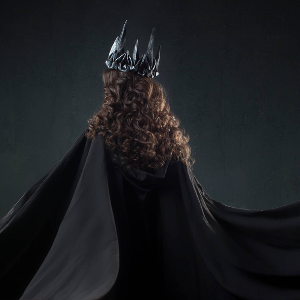 Portrait of a Gothic Princess. Beautiful young brunette woman in metal crown and black cloak. - Fotografie, Obrázek