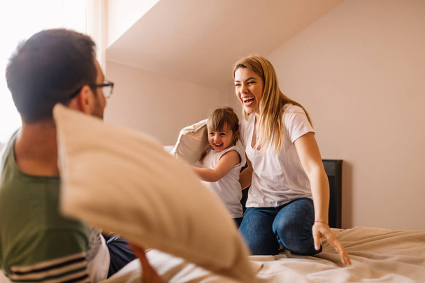 šťastná rodina s polštář bojovat v posteli doma - Fotografie, Obrázek