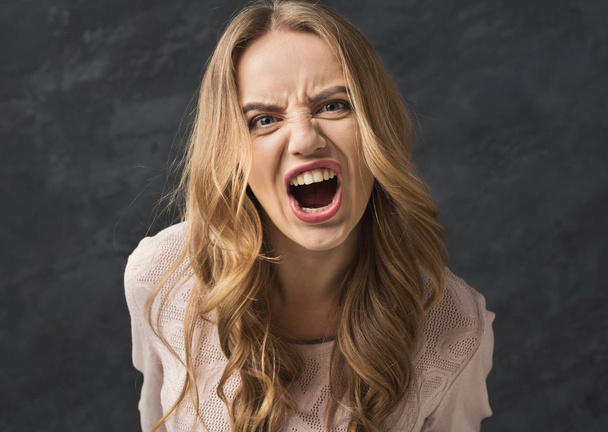 Jonge vrouw op grijze achtergrond schreeuwen - Foto, afbeelding