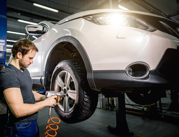 mechanic changing car wheel in auto repair garage - Photo, image