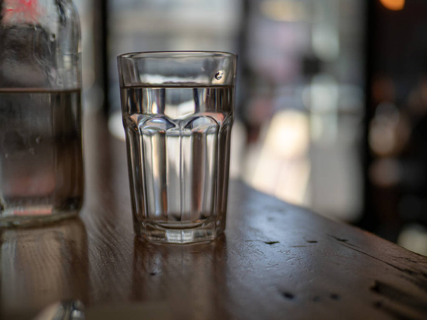Glass of water sitting near a restaurant entrance  - 写真・画像
