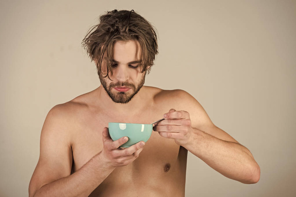 Man with wet hair eat breakfast on grey background - Zdjęcie, obraz