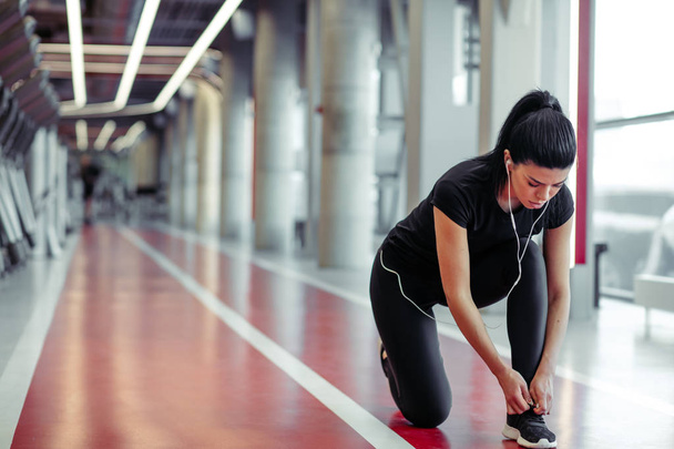 dívka dolů dělat tkaničky ve fitness tělocvičně před spuštěním cvičení - Fotografie, Obrázek