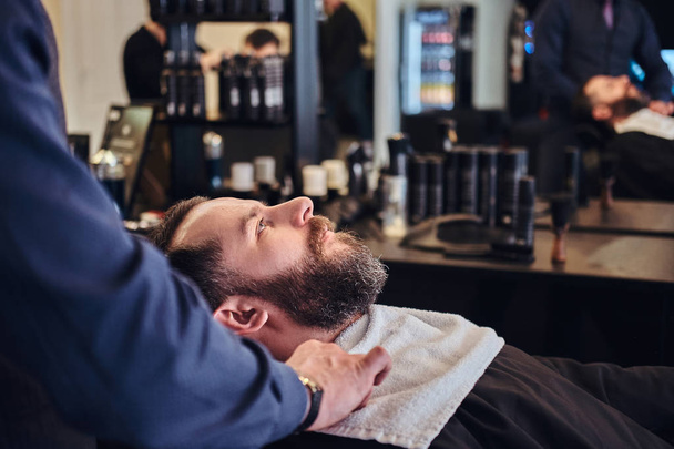 Maître coiffeur prépare le visage pour le rasage dans le salon de coiffure
. - Photo, image