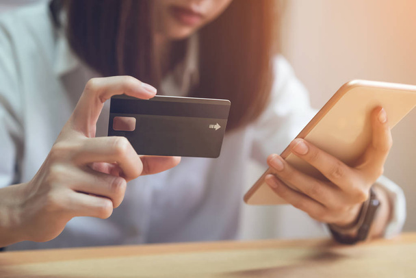 Γυναίκα κρατώντας πληρωμή πιστωτικών καρτών σε απευθείας σύνδεση και χρησιμοποιώντας το smartphone για το κατάστημα μέσω της ιστοσελίδας. Έννοιες online αγορές για ευκολία. - Φωτογραφία, εικόνα