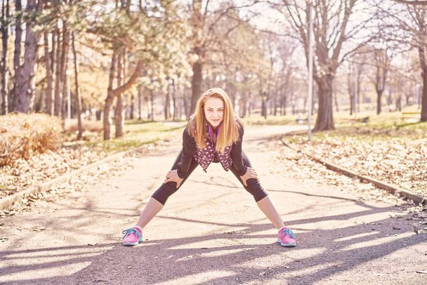 Krásná sportovkyně s smartphone cvičení v parku - Fotografie, Obrázek