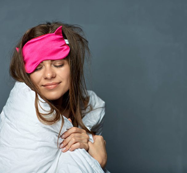 Vrouw met masker in de deken en blinddoek de ogen voor slapen op grijze achtergrond, slaap concept - Foto, afbeelding