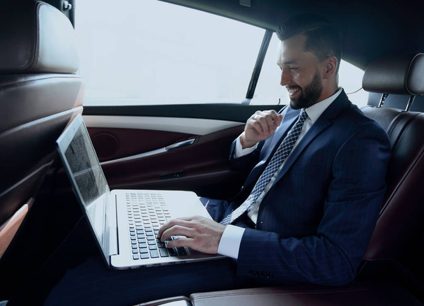 Homme d'affaires tapant du texte sur un ordinateur portable tout en étant assis dans la voiture
 - Photo, image