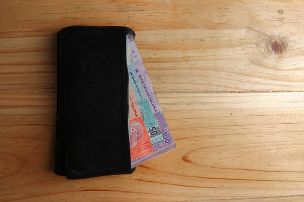 Portefeuille ouvert en cuir pour homme avec billets Malaisie et carte de crédit à l'intérieur sur un fond en bois
. - Photo, image