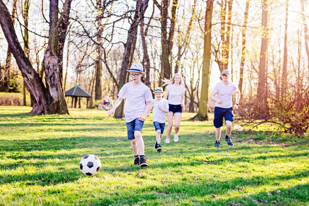 Familie spielt Fußball auf grünem Rasen im Park. - Foto, Bild