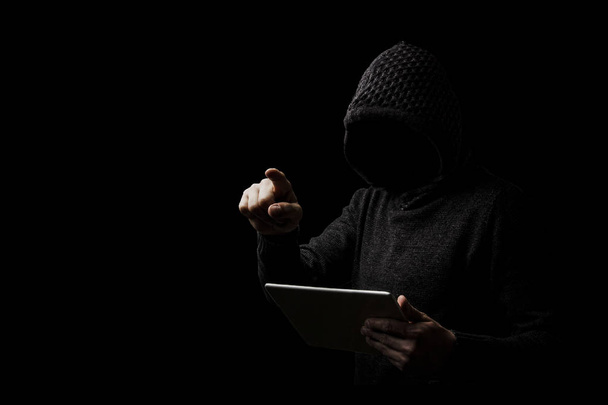 Un hombre impersonal en una capucha con una tableta en su h izquierda
 - Foto, imagen