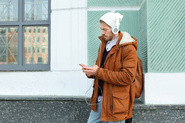 Portrait of handsome hipster with headphones listening to music outdoors - 写真・画像