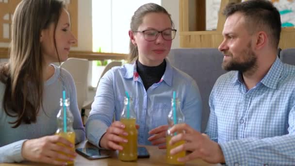 Τρεις φίλοι κάθονται σε ένα καφενείο, πιείτε το χυμό και να διασκεδάσουν επικοινωνία - Πλάνα, βίντεο