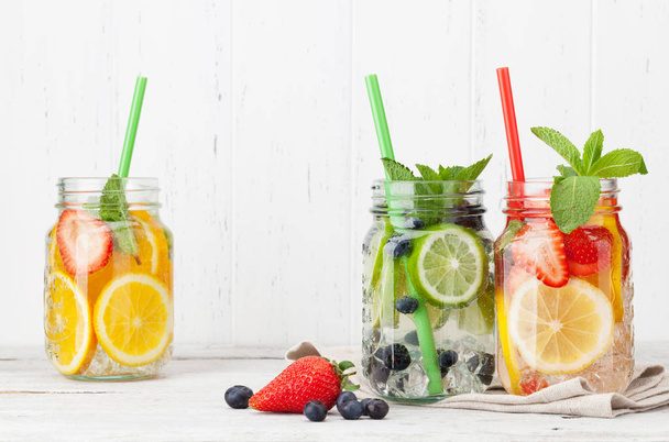 Frascos de limonada fresca con frutas de verano de color y bayas sobre fondo gris, vista superior con espacio para copiar
 - Foto, imagen