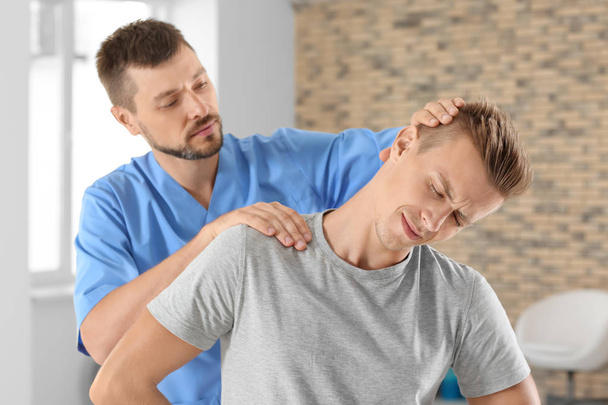 Physiotherapist working with young male patient in clinic - Foto, Imagen