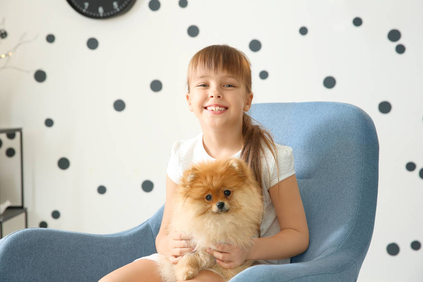 Linda chica con perrito en sillón en casa
 - Foto, Imagen