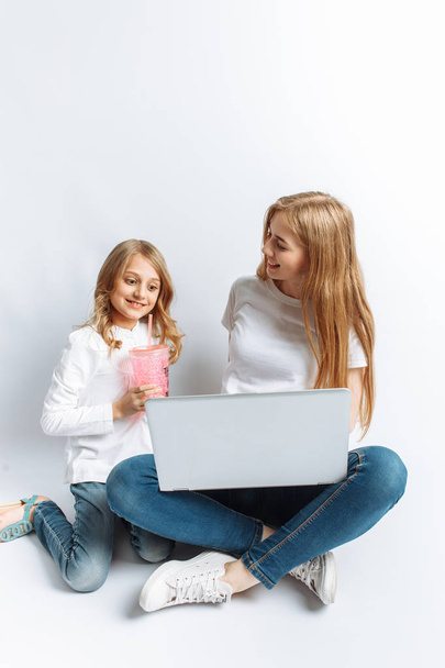 A sister or a young mother with her daughter watching a movie on my laptop, fun, laughing, Studio, isolated - Fotografie, Obrázek