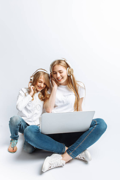 A sister or a young mother with her daughter watching a movie on my laptop, fun, laughing, Studio, isolated - Valokuva, kuva