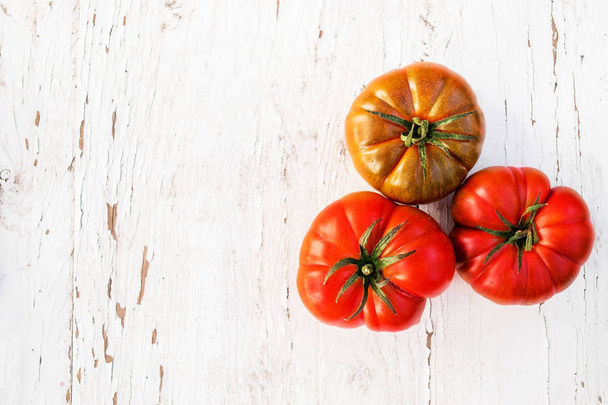 whole fresh ripe tomatoes on bright wooden background - Foto, Imagem