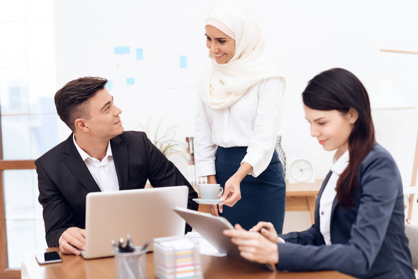 Mulher árabe no hijab trabalhando no escritório em conjunto com colegas
 - Foto, Imagem
