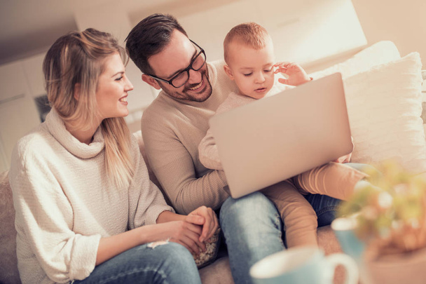 Jonge familie kijken Beeldverhaal over laptop samen. Personen, familie, liefde en geluk concept. - Foto, afbeelding