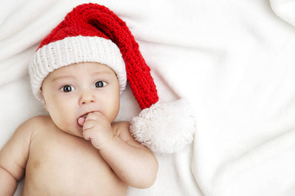 bambino sdraiato a letto, con un cappello da Babbo Natale
. - Foto, immagini