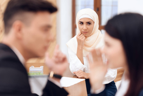 man and woman talking while woman in hijab waiting them - Photo, image
