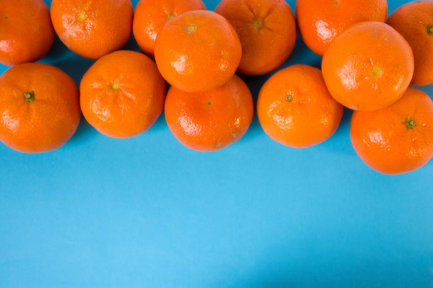 La mandarina o mandarinas frescas de frutas jugosas maduras en cáscara de naranja se encuentran en la vista superior de la mesa azul aisladas. Hay un campo abierto para la inscripción
 - Foto, Imagen
