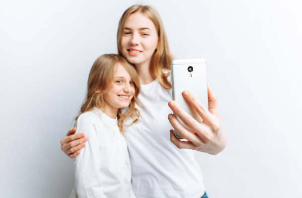 Mom or older sister makes selfie little girl, happy family, photo Studio, isolated - Фото, изображение