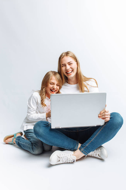 A sister or a young mother with her daughter watching a movie on my laptop, fun, laughing, Studio, isolated - Фото, зображення
