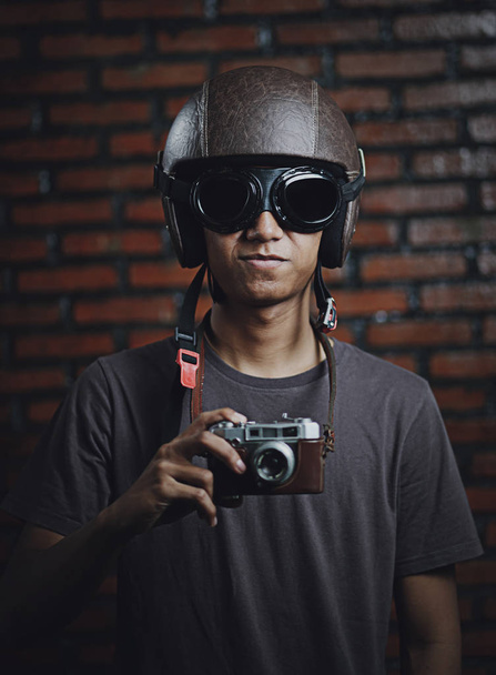 asiatische Mann mit Oldtimer-Kamera trägt Retro-Helm auf Ziegel w - Foto, Bild
