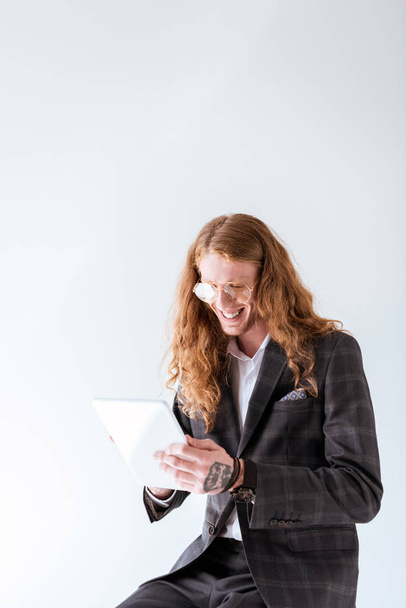 sonriente hombre de negocios tatuado con cabello rizado usando tableta aislada en blanco
 - Foto, imagen