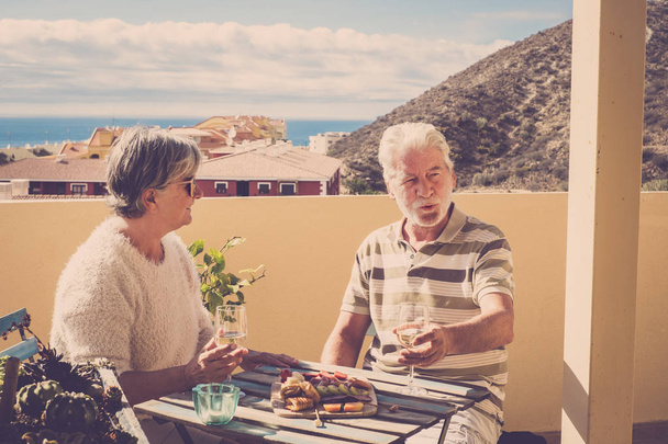 Dachterrasse Szene für ältere Paare, während einige natürliche Nahrung für die Heidepflege essen. sie lächelt ihn an. Meerblick von der Terrasse. - Foto, Bild
